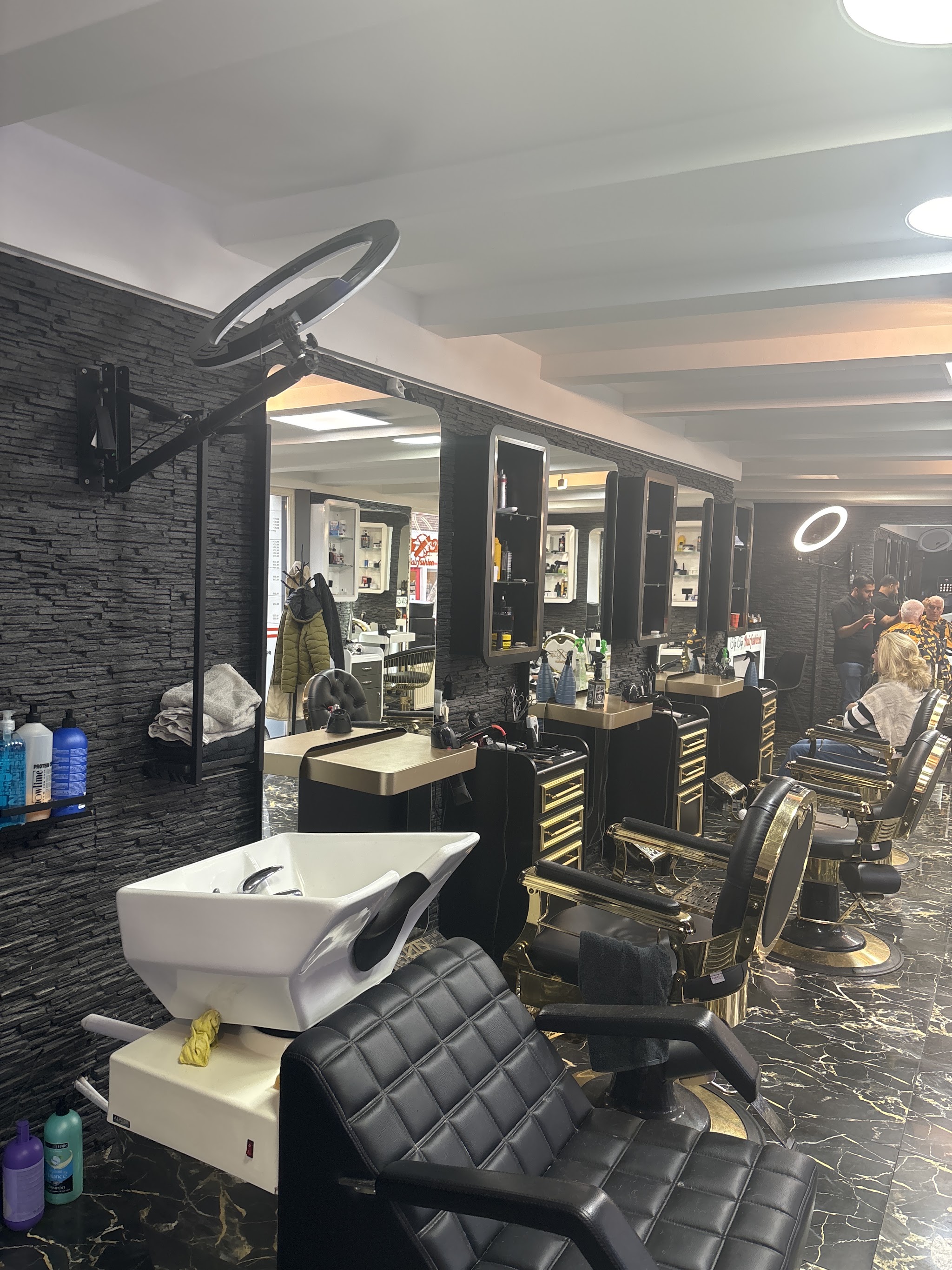 Interieur met een wasstoel, leren kappersstoelen met gouden lijsten, spiegels en een donkere stenen wand