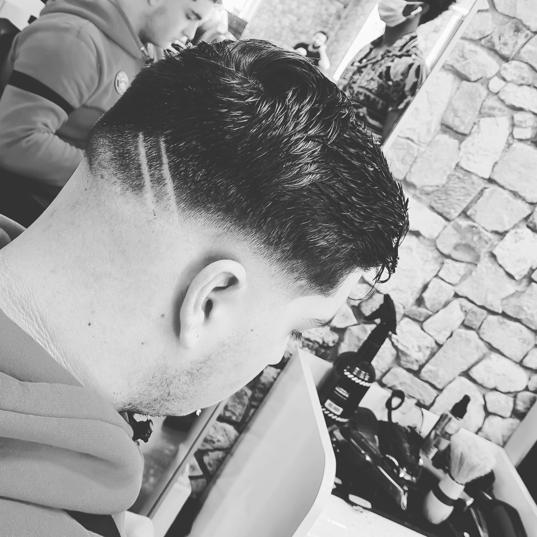 Een vers geknipte skin fade met een strak lijntje, in zwart-wit