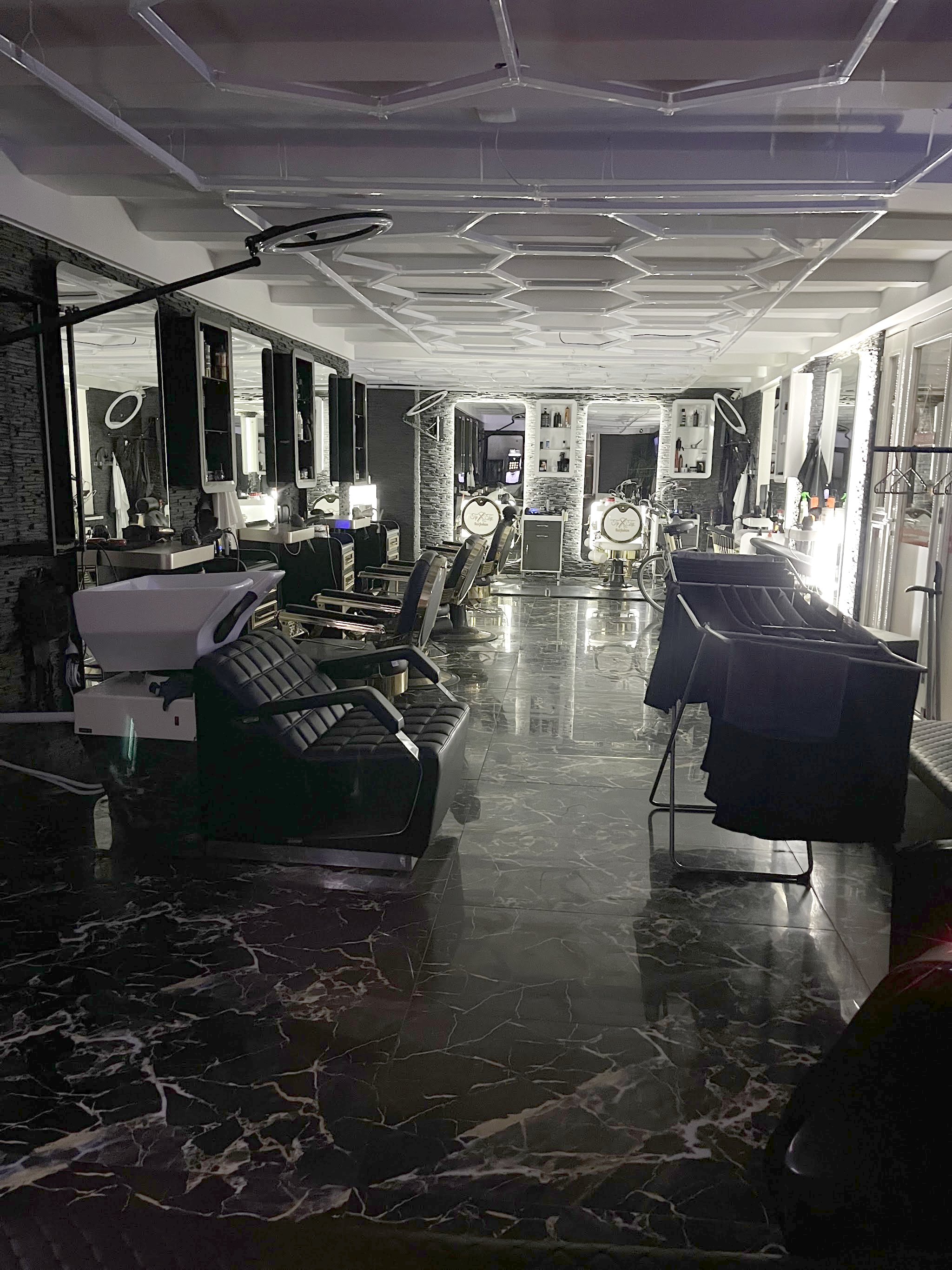 De lange rij kappersstoelen in de zaak, met de zwarte marmeren vloer
